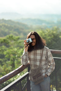 Man photographing while standing by railing