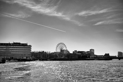 Buildings by river against cloudy sky