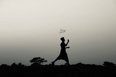 Silhouette man standing by tree against sky during sunset