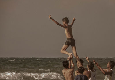 Low section of people at beach against sky