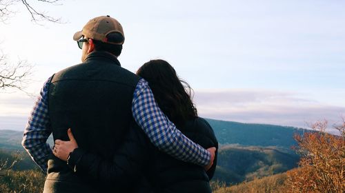 Rear view of people standing on mountain against sky