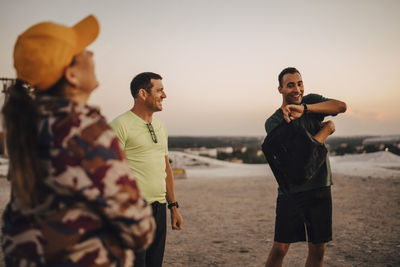 Happy male and female athletes standing on land during sunset