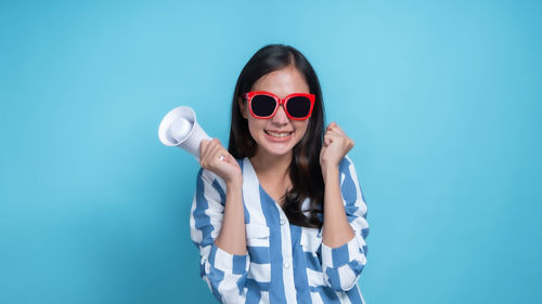 Portrait of a smiling young woman against blue background