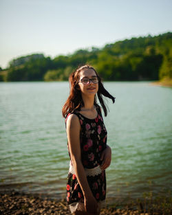 Young woman standing against lake