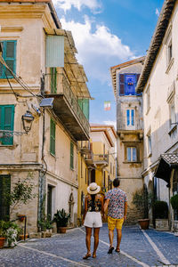 Rear view of people walking on street amidst buildings