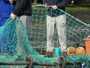 Low section of men holding fishing net while standing outdoors