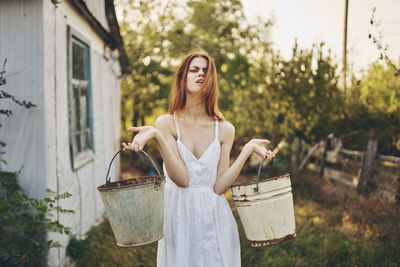 Young woman holding umbrella standing against plants