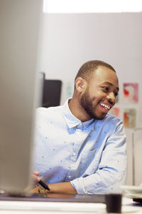 Happy male illustrator holding digitized pen while working at desk in creative office