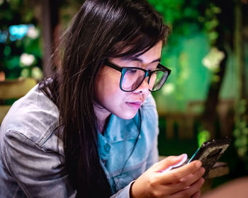 Close-up of girl using mobile phone outdoors