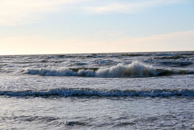 Waves rushing towards shore against sky