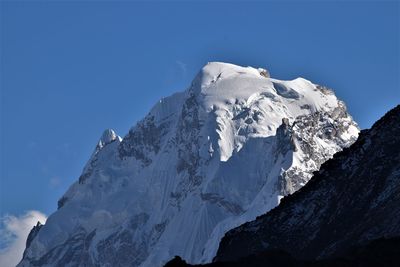 Low angle view of snowcapped mountains against blue sky