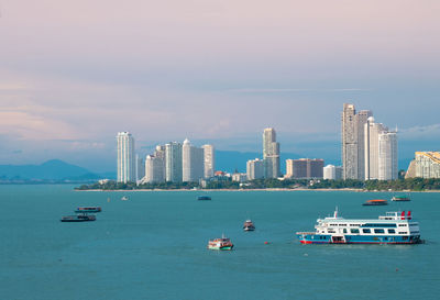 Boats in sea by buildings against sky