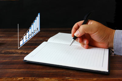 Midsection of person holding book on table