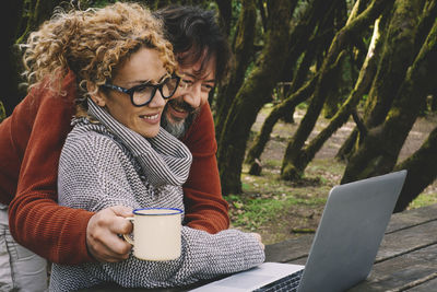 Happy couple using laptop outdoors