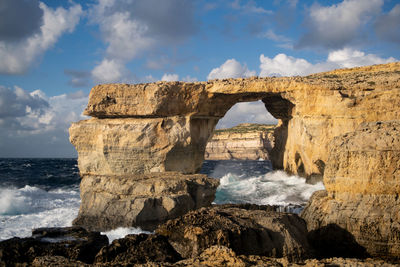 Rock formations on beach against sky