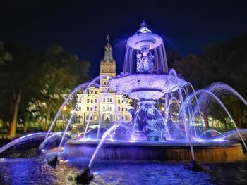 Illuminated fountain building against sky at night