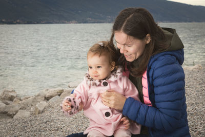 Mother and daughter sitting at lakeshore