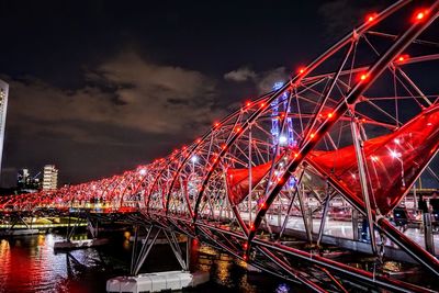 Illuminated bridge over river against sky at night