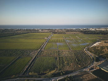 Aerial view of agricultural field by sea against sky