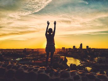 Silhouette man and cityscape against sky during sunset