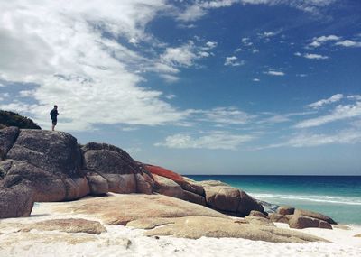 Man standing on large rock seaside