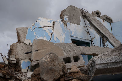 Low angle view of damaged rock on land against sky