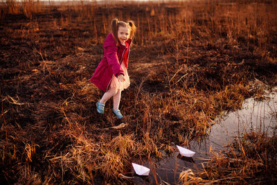 Girl in the spring on the creek launches paper boats