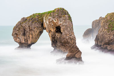 Rock formation in sea against sky