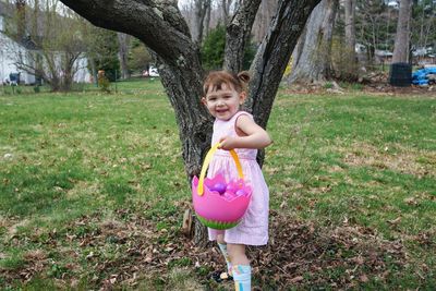 Portrait of smiling girl holding tree trunk