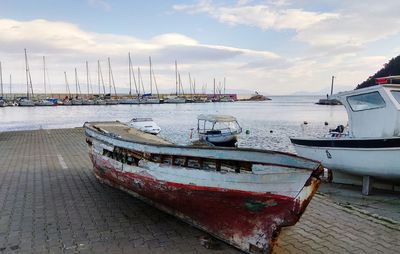 Sailboats moored at harbor against sky