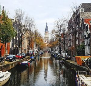 Canal amidst buildings in city against sky