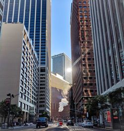 City street by modern buildings against sky