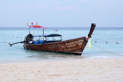 Boat moored on beach against sky