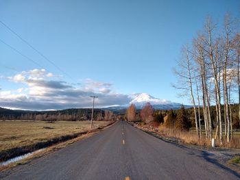 Empty road amidst landscape against sky