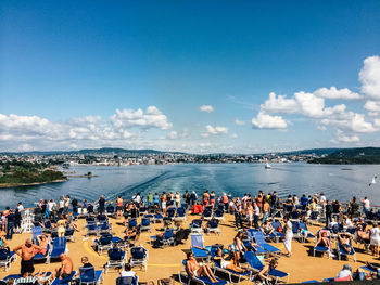 People at observation point by sea against sky