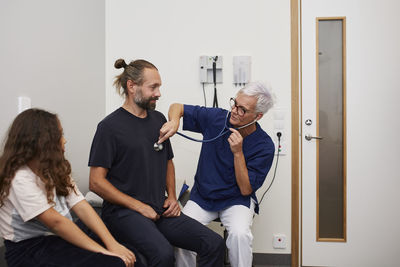 Doctor examining father and daughter in health center