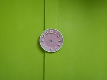 Close-up of clock on green wall