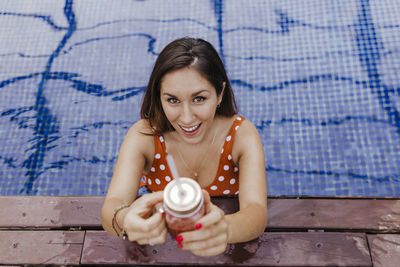 Portrait of a smiling young woman holding swimming pool