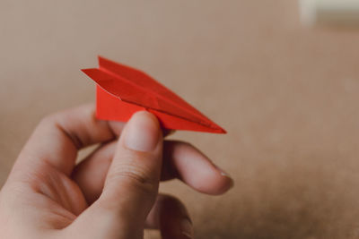 Cropped hand of person holding red origami