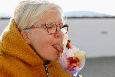 Close-up of senior woman licking ice cream in glass