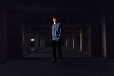 Full length of young man standing against illuminated wall