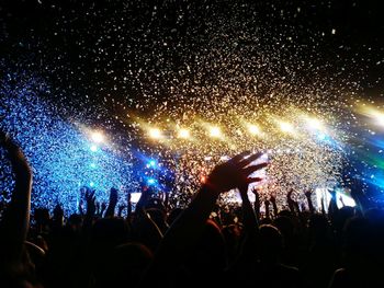 Crowd enjoying against illuminated stage with confetti during music concert