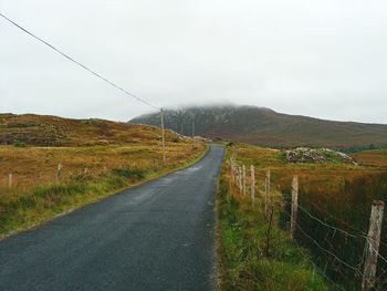 Road amidst field against sky