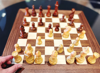 Cropped hand of woman picking up a chess piece 