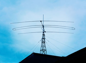 Low angle view of silhouette cables against blue sky