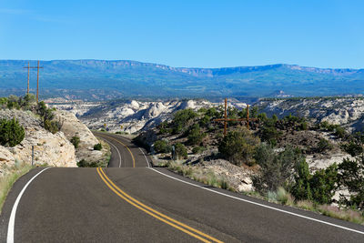 Scenic view of road by mountains against sky