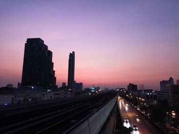 Illuminated buildings in city against sky during sunset