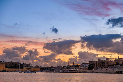 Panoramic view of sea and buildings against sky during sunset
