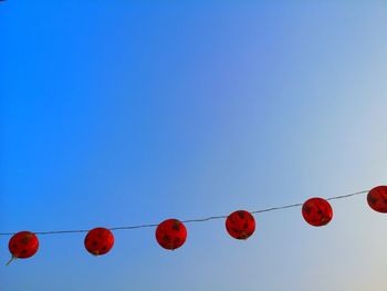 Low angle view of lanterns hanging against clear blue sky