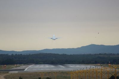 Airplane flying over mountain against sky